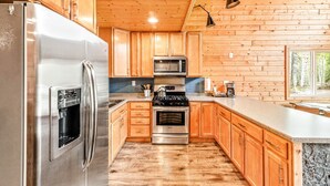 A modern kitchen with wooden cabinets, stainless steel appliances, and a granite countertop.