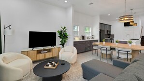A modern living room with a flat-screen TV, a coffee table, and seating. - The Krakow | Sleeps 16 (Houston)