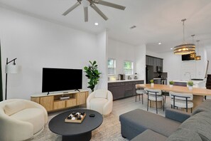 A modern living room with a flat-screen TV, a coffee table, and seating. - The Krakow | Sleeps 16 (Houston)