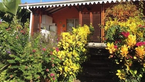 A house with a porch, surrounded by colorful plants and flowers. - Villa Manguier, a heavenly vacation!
Swimming pool, sea view, car rental (Rivière-Salée)