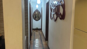 Un pasillo estrecho con suelo de madera, una alfombra roja, un espejo y un adorno en la pared.