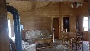 Een houten blokhutinterieur met een bank, eettafel en stoelen.