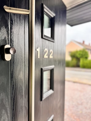 A modern door with a keyhole and a number plate reading "122".