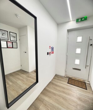 A hallway with a large mirror, a fire action sign, and a door with a handle.