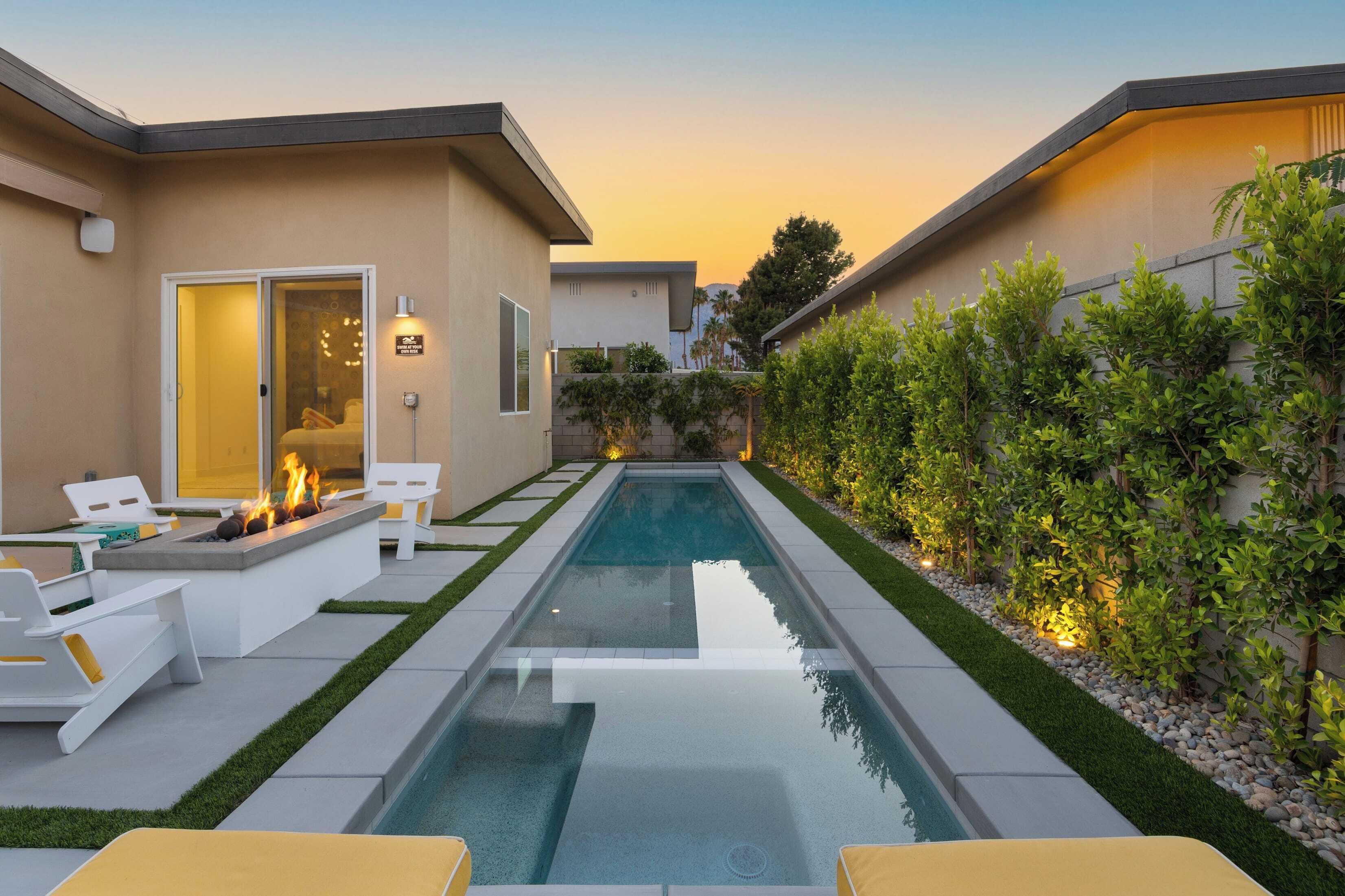 A modern outdoor pool area with lounge chairs, a fire pit, and a well-maintained garden.