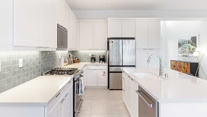 A modern kitchen with white cabinetry, stainless steel appliances, and a tiled backsplash. - Lumen at Tahquitz: New Build With Pool, Fire Pit & Designer Interiors (Palm Springs)