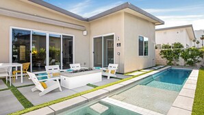 Ein modernes Haus mit Pool, Sitzgelegenheit im Freien und einem gepflegten Garten.
