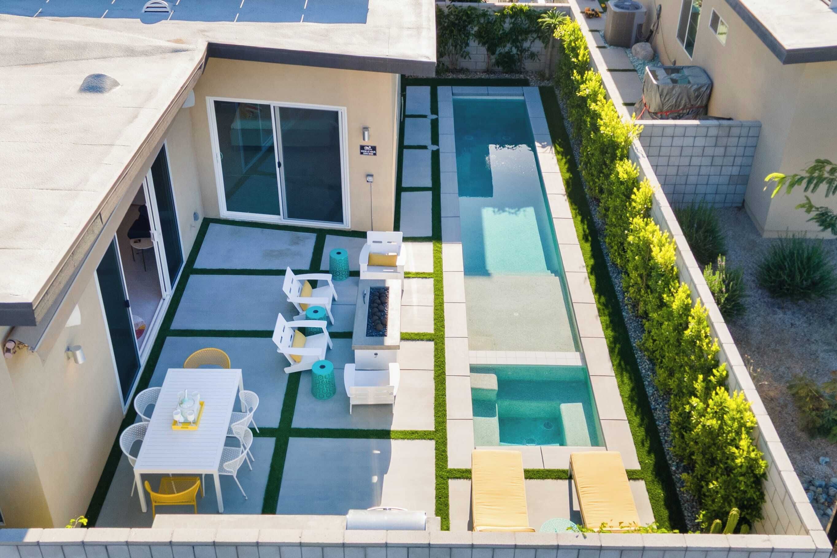 Un área de piscina en la azotea con mesa y sillas, un jacuzzi y una pequeña zona de estar.