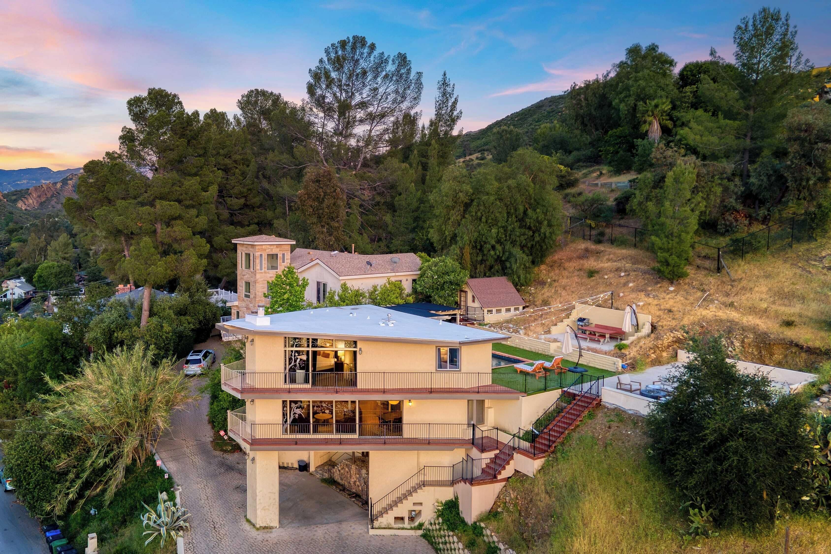 A multi-story house with a balcony, a driveway, and a fenced yard.