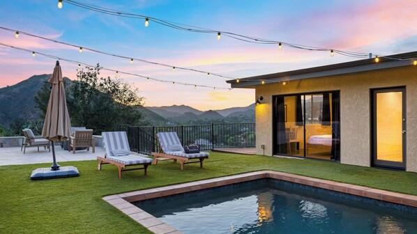 A pool with a view of mountains, a patio with lounge chairs, and string lights. - Designer Retreat w/ Pool, Firepits, Panoramic Views The Lake House at Malibu (Agoura Hills)