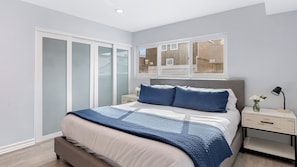 A bedroom with a bed, a nightstand, a window, and a sliding door.