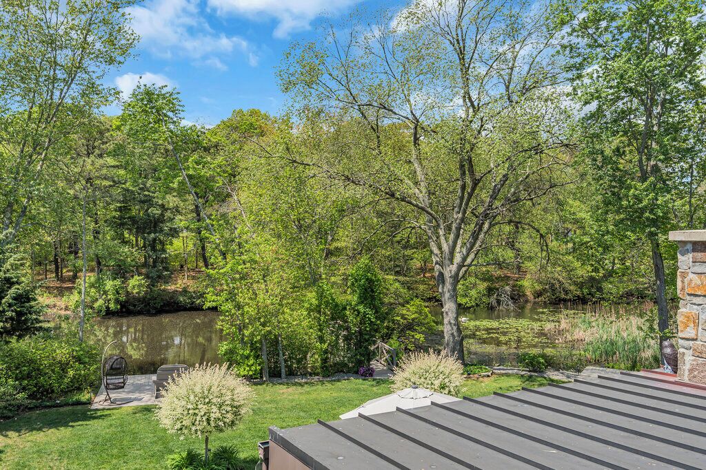 A serene outdoor area with a pond, lush greenery, and a stone building.