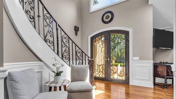 Un vaste espace de vie agrémenté d’un escalier en courbe, d’un coin salon confortable avec deux fauteuils, d’une petite table ronde ornée d’une plante en pot et d’une grande porte-fenêtre coulissante donnant sur un espace extérieur.