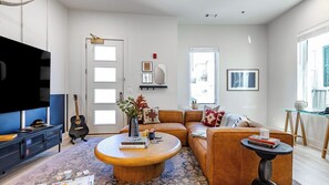 A living room with a sofa, coffee table, and a TV. - Sleeps 24, 2 Units Mins to Downtown Outrider by Avantstay (Nashville)