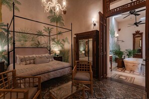 Relax in a serene bedroom with a four-poster bed, nightstand, and mirror, surrounded by a tropical theme.