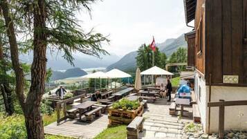 An outdoor seating area with tables and chairs, overlooking a mountainous landscape.