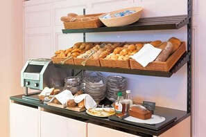 A breakfast buffet with bread, pastries, and condiments.