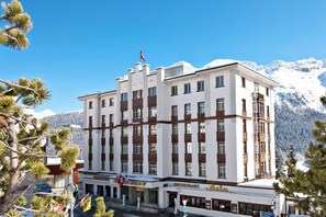 A multi-story hotel with a prominent entrance, flags, and a mountain backdrop. - Hotel Schweizerhof St. Moritz (Saint Moritz)