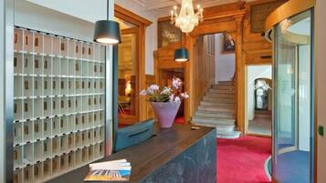 A reception area with a marble counter, a wall-mounted keycard holder, a potted plant, and a staircase leading to upper floors.