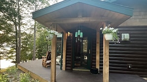 A wooden cabin with a covered porch, stone steps, and a bench. - Charming 3-bedroom cabin with WiFi, AC in lovely Eagle River sleeps 8 people. (Eagle River)