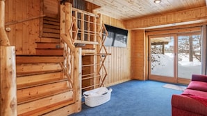 A wooden interior with a staircase, a television, and a view of the snowy outdoors. - Charming 3-bedroom cabin with WiFi, AC in lovely Eagle River sleeps 8 people. (Eagle River)