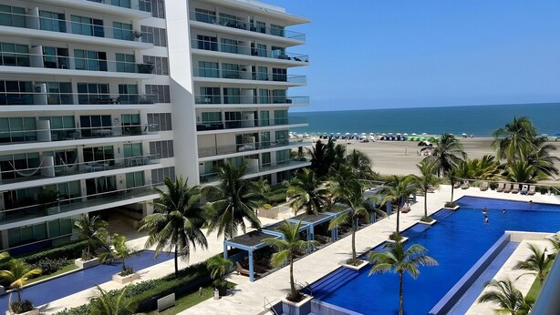 Un hôtel moderne doté de nombreux balcons offrant une vue sur une plage et une piscine.