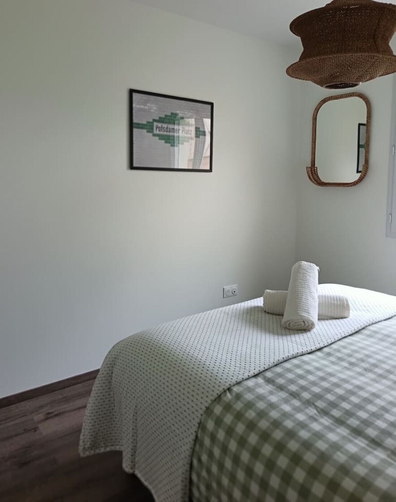 Une chambre à coucher avec un lit, un oreiller, un miroir fixé au mur et un tableau encadré.