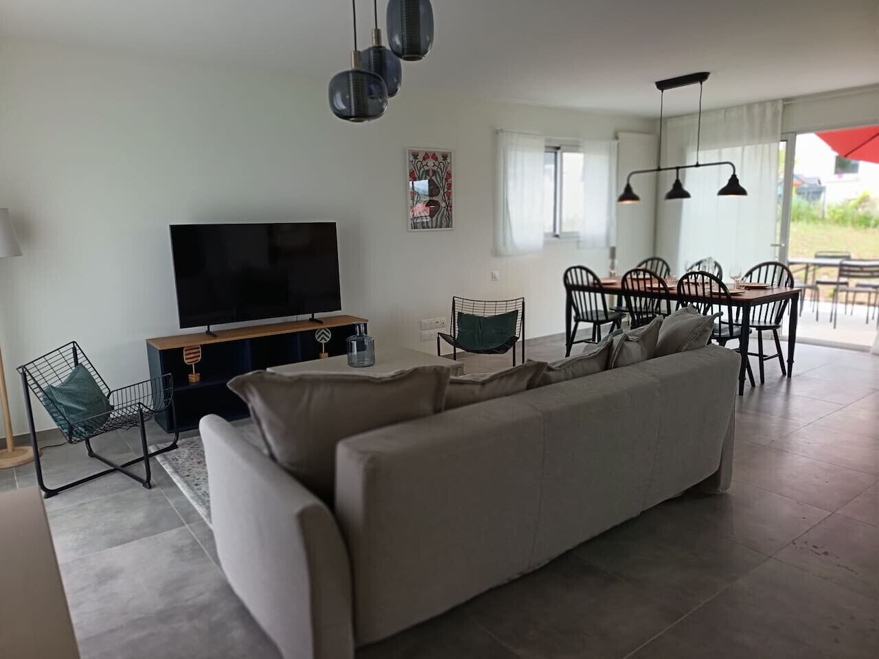 Un salon moderne comprenant un grand canapé, un téléviseur, un coin repas avec des chaises et une table.