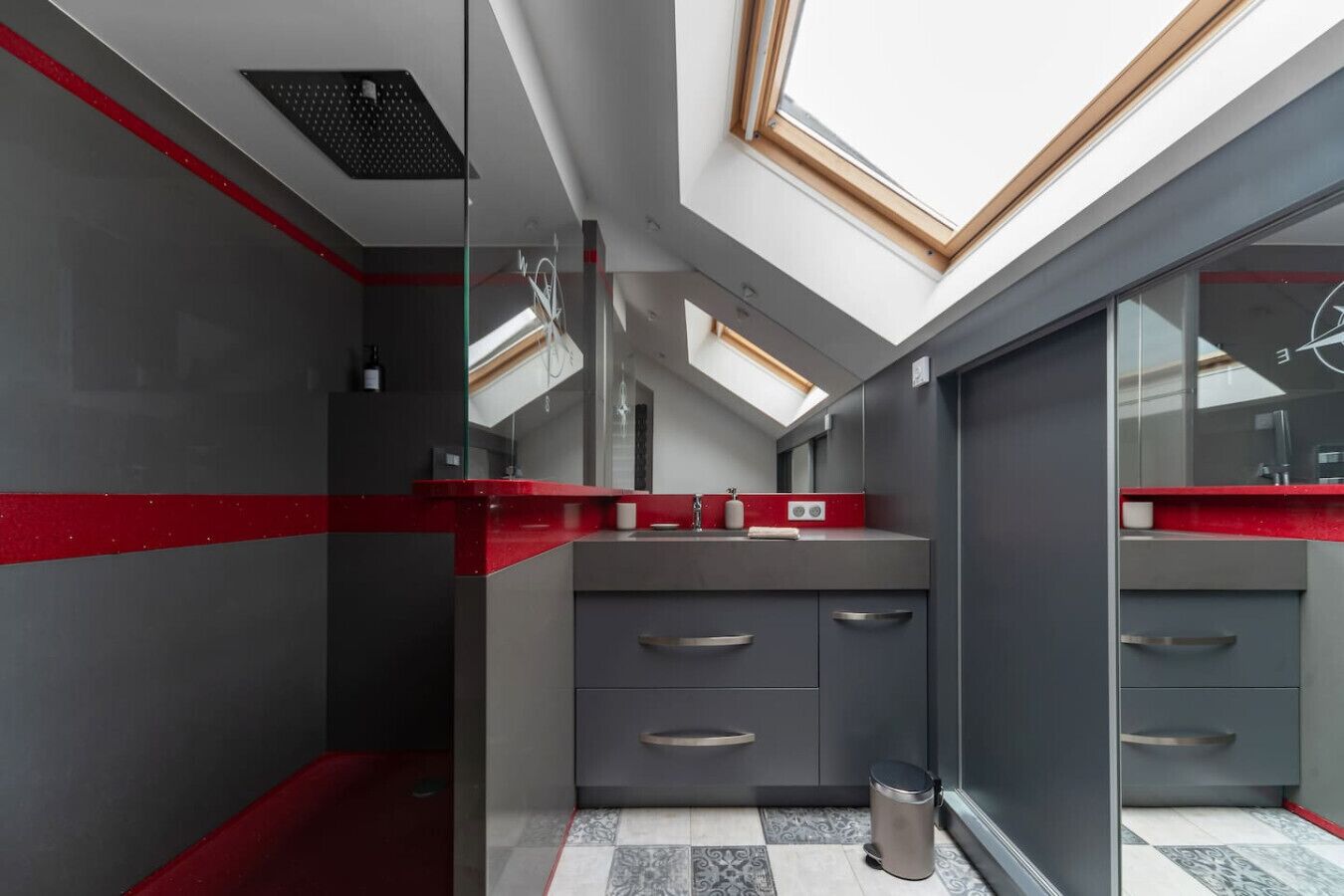 Un baño moderno con tragaluces, una pared de acento roja y suelo de baldosas.