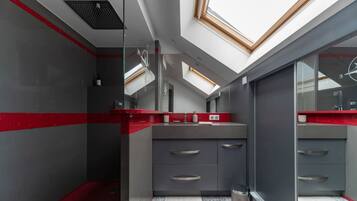 Un baño moderno con tragaluces, una pared de acento roja y suelo de baldosas.