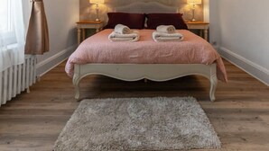 Un dormitorio con cama, dos lámparas de noche, un radiador y una lámpara colgante.