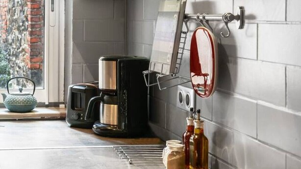 Una cocina moderna con estufa a gas, cafetera y un tendedero.