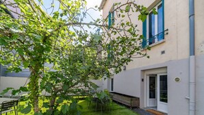 Ein Innenhof mit Baum, Bank und Gebäude mit blauen Fensterläden.