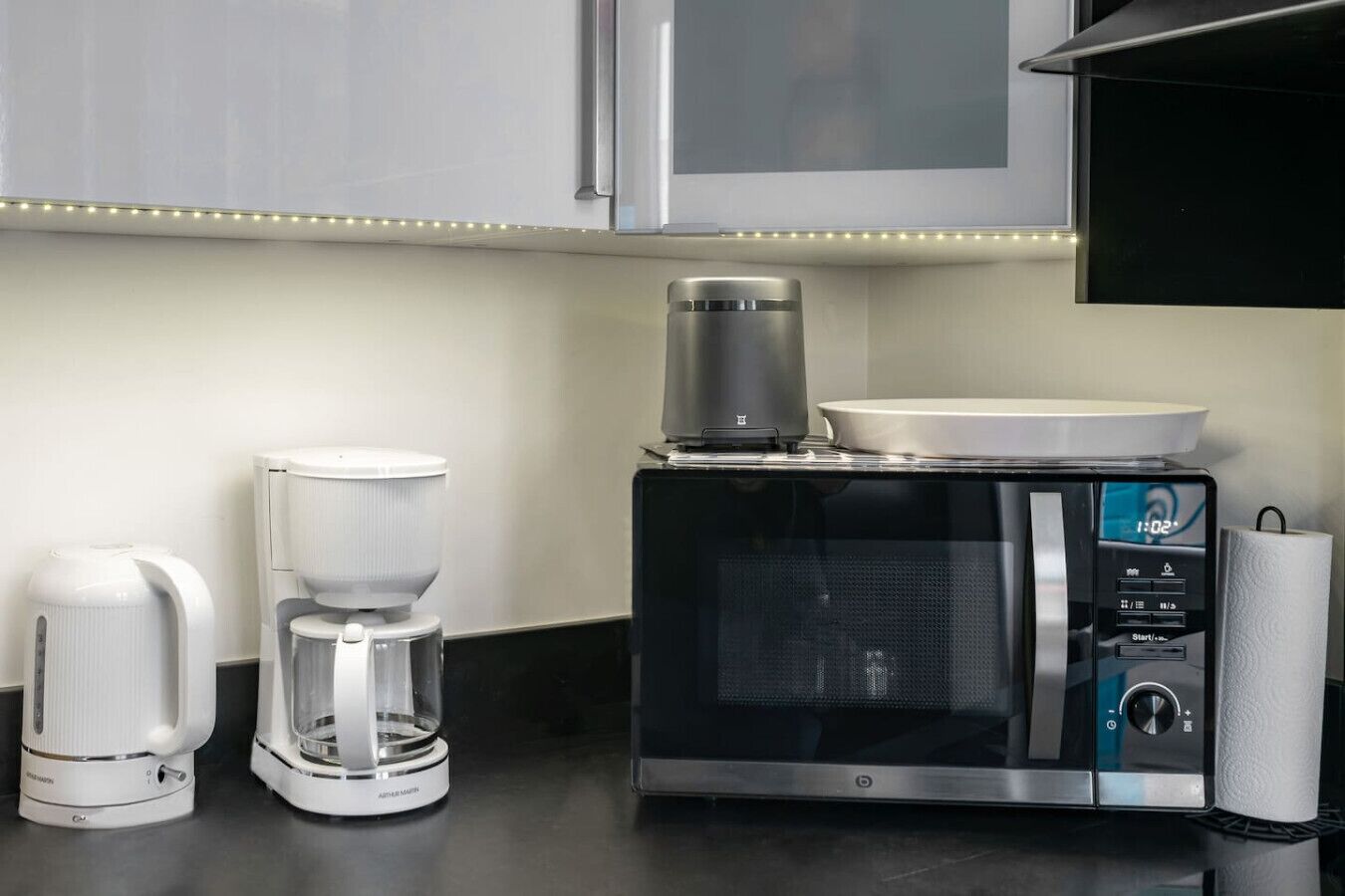 A kitchen with a coffee maker, a microwave, and a kettle.