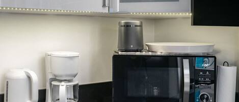 A kitchen with a coffee maker, a microwave, and a kettle.