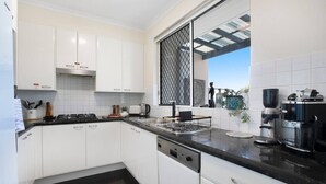 Una cocina moderna con armarios blancos, encimera negra y una máquina de café.