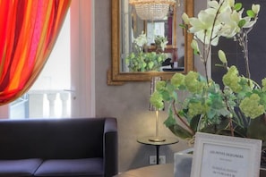 A hotel lobby with a sofa, a mirror, and a vase of flowers. - Best Western Hôtel Brittany la Baule Centre Et Plage (La Baule-Escoublac)