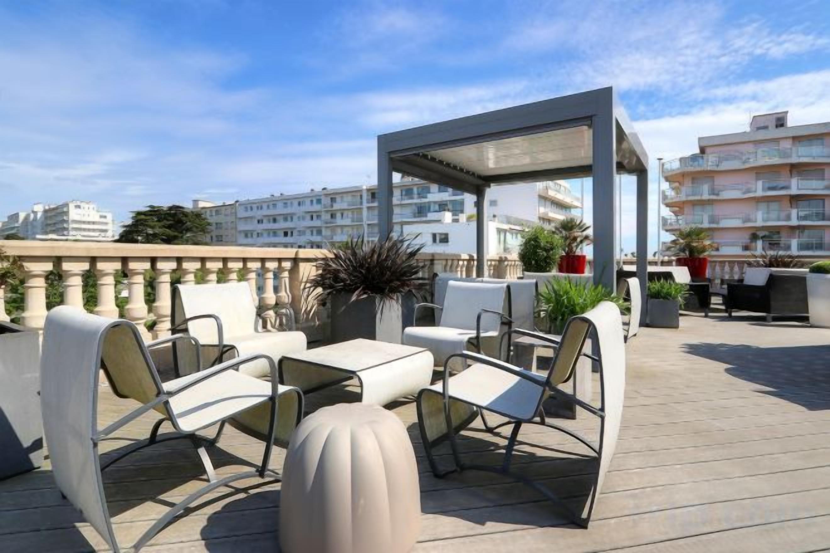 A rooftop terrace with outdoor seating, a pergola, and a view of the cityscape.