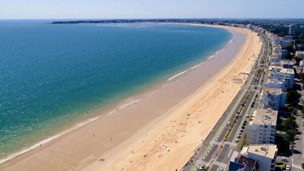 An aerial view of a beach with a clear blue ocean, sandy shore, and a row of buildings along the coastline. - Best Western Hôtel Brittany la Baule Centre Et Plage (La Baule-Escoublac)