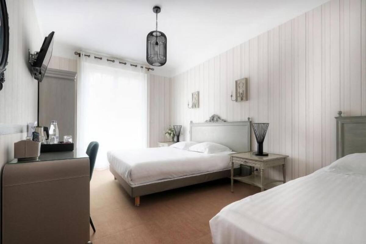 A hotel room with a bed, bedside table, lamp, and a desk with a chair.