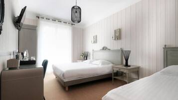 A hotel room with a bed, bedside table, lamp, and a desk with a chair.