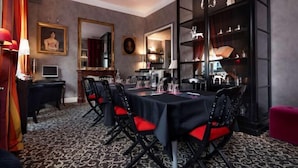 A dining area with a long table, black chairs with red cushions, a patterned carpet, and a mirror on the wall. - Best Western Hôtel Brittany la Baule Centre Et Plage (La Baule-Escoublac)