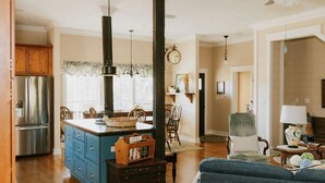 Un salon spacieux avec un canapé bleu, une table basse en bois et un coin repas agrémenté d’un lustre.