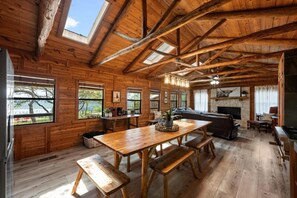 Cozy cabin with a dining table, seating area, and fireplace, offering views of the surrounding landscape.