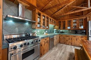 Modern kitchen with a stainless steel stove, oven, and glass-fronted cabinets.