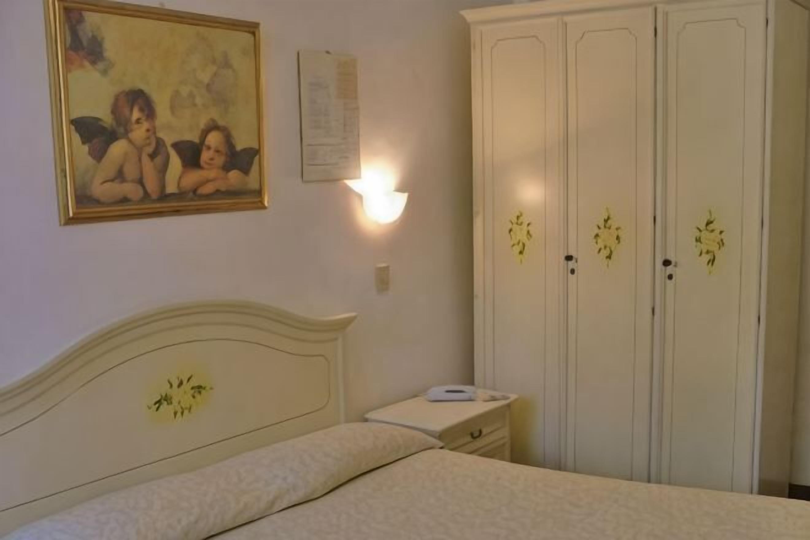 Un dormitorio con cama, mesita de noche, armario y luz empotrada en la pared.