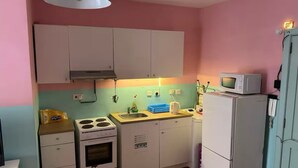 Una cocina compacta con armarios blancos, estufa, fregadero y microondas.