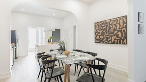 A modern dining area with a glass table, black chairs, and a white interior. - Sleeps 28 2 Units Near DT Nashville Outrider by Avantstay (Nashville)