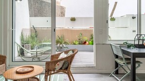 Un intérieur moderne avec une porte vitrée donnant sur un balcon aménagé avec des sièges et des plantes.