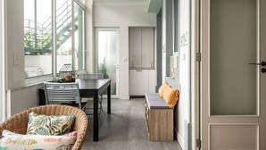 Un espace de vie compact comprenant un coin repas, une petite kitchenette et un coin salon confortable près de la fenêtre.